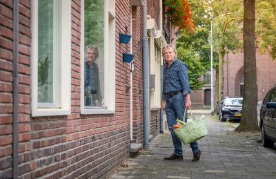 Man met boodschappentas op straat bij voordeur