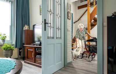 Vrouw in hal met hondje en rollator